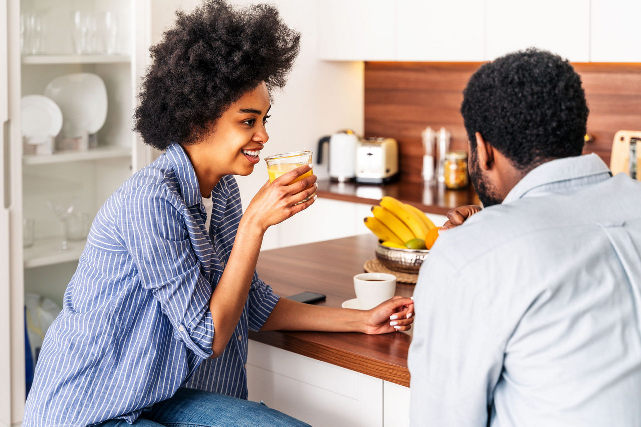 Woman drinking orange juice with her husband in their kitchen