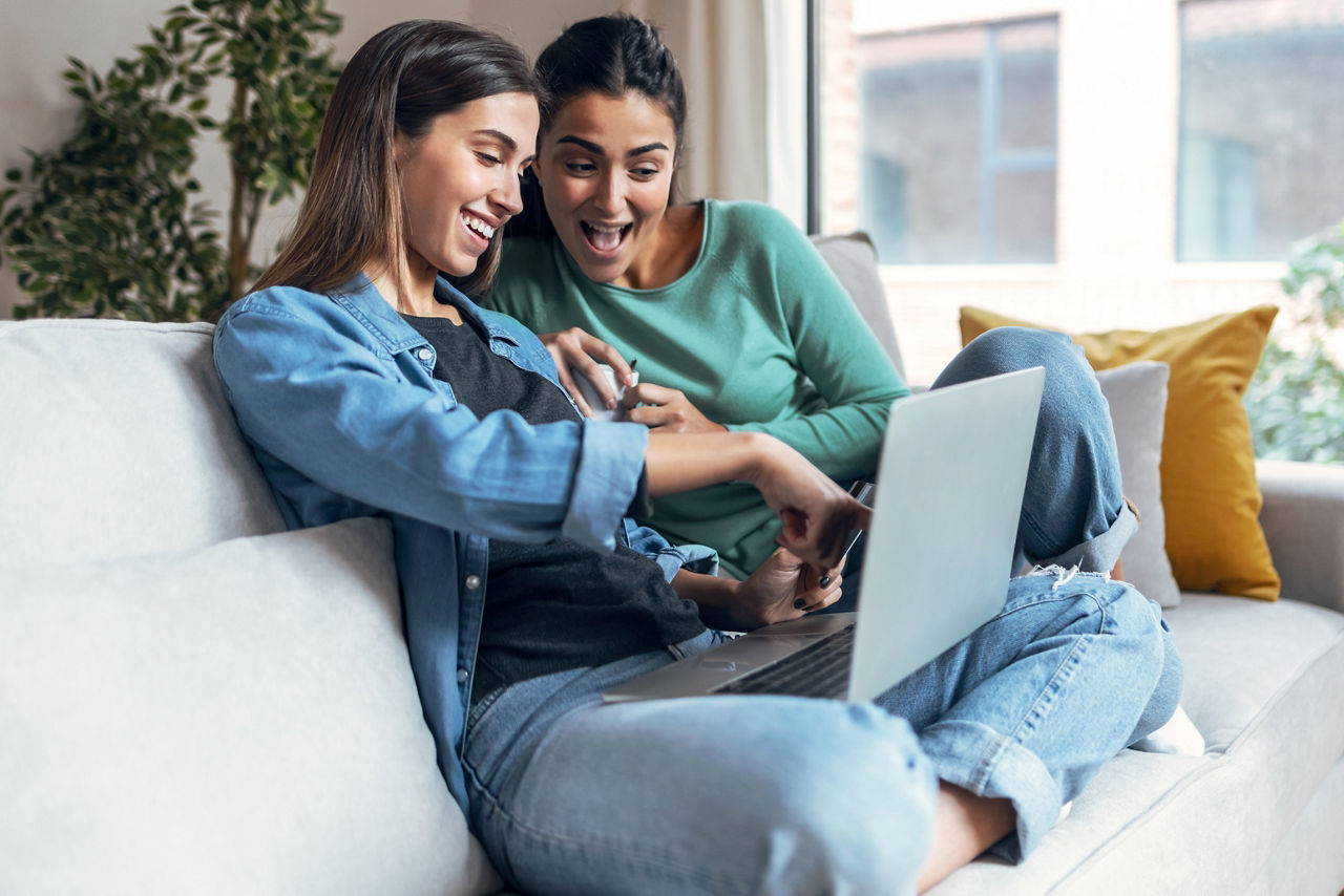 Shot of two happy beautiful women doing a video call sitting on the couch at home.