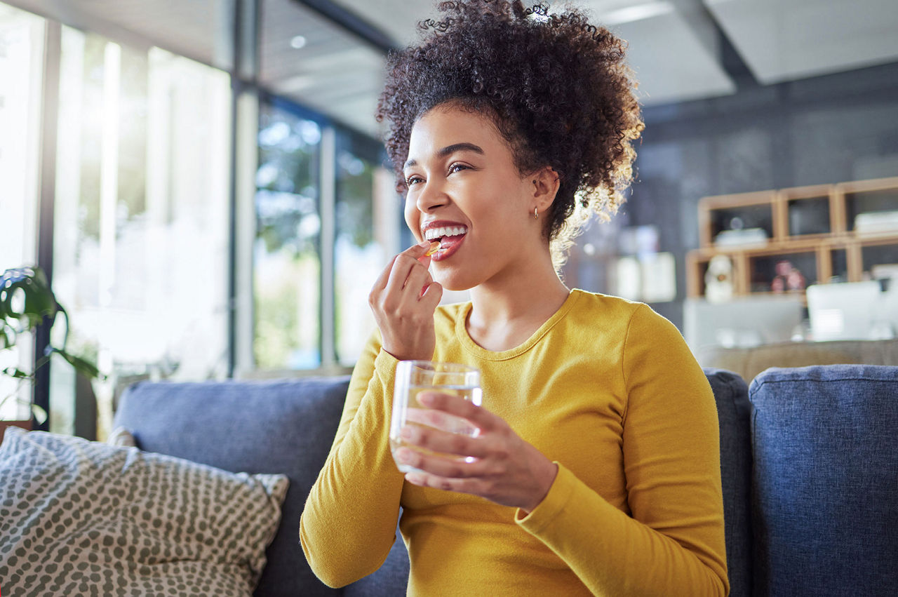 woman taking supplement in living room