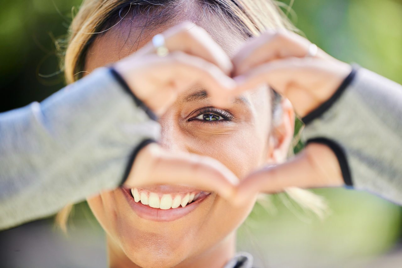 Woman smiling and forming a heart with her hands.